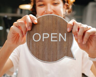 image of young woman holding an open sign for her business - How to Make the Most of Small Business